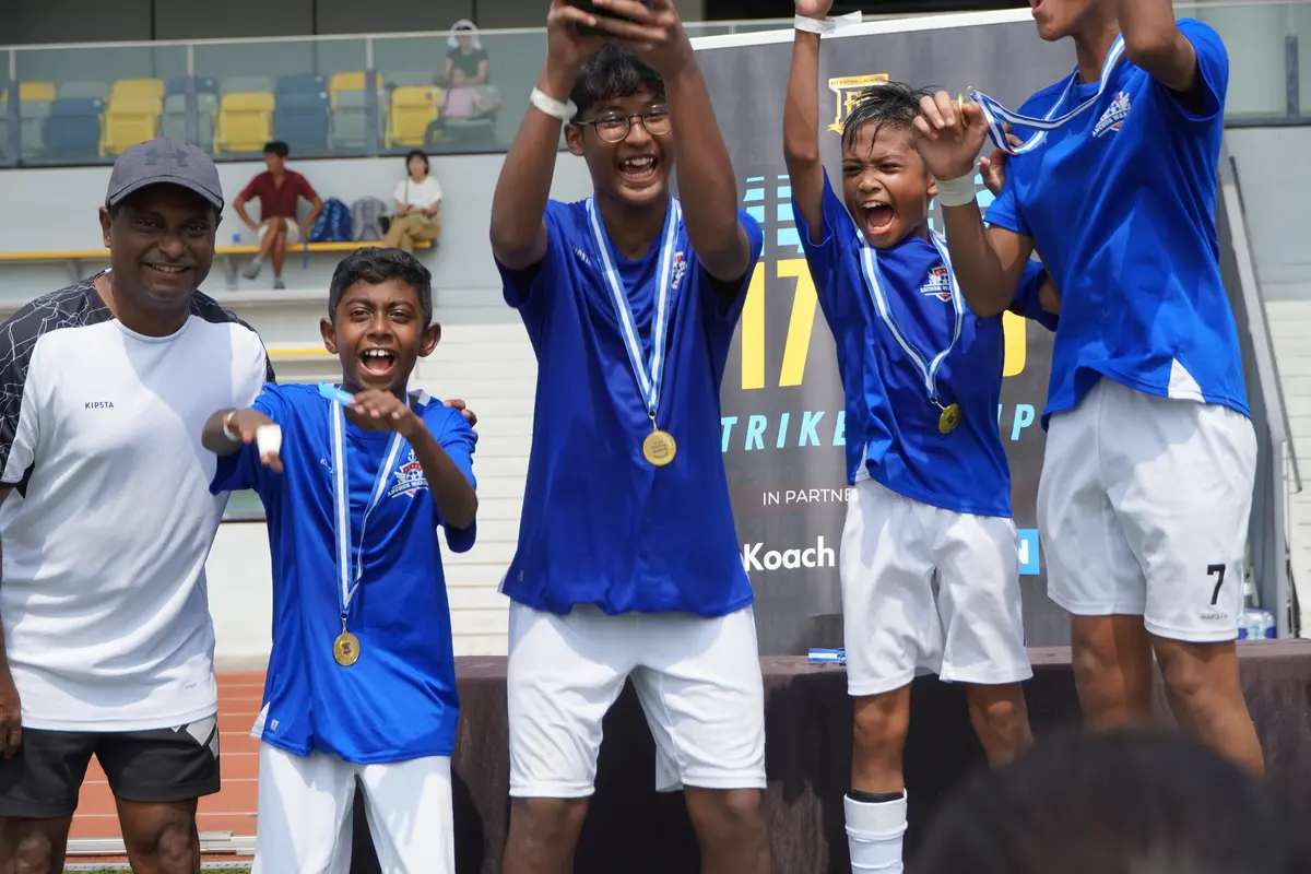 Players celebrating with medals and the Strikers Cup trophy